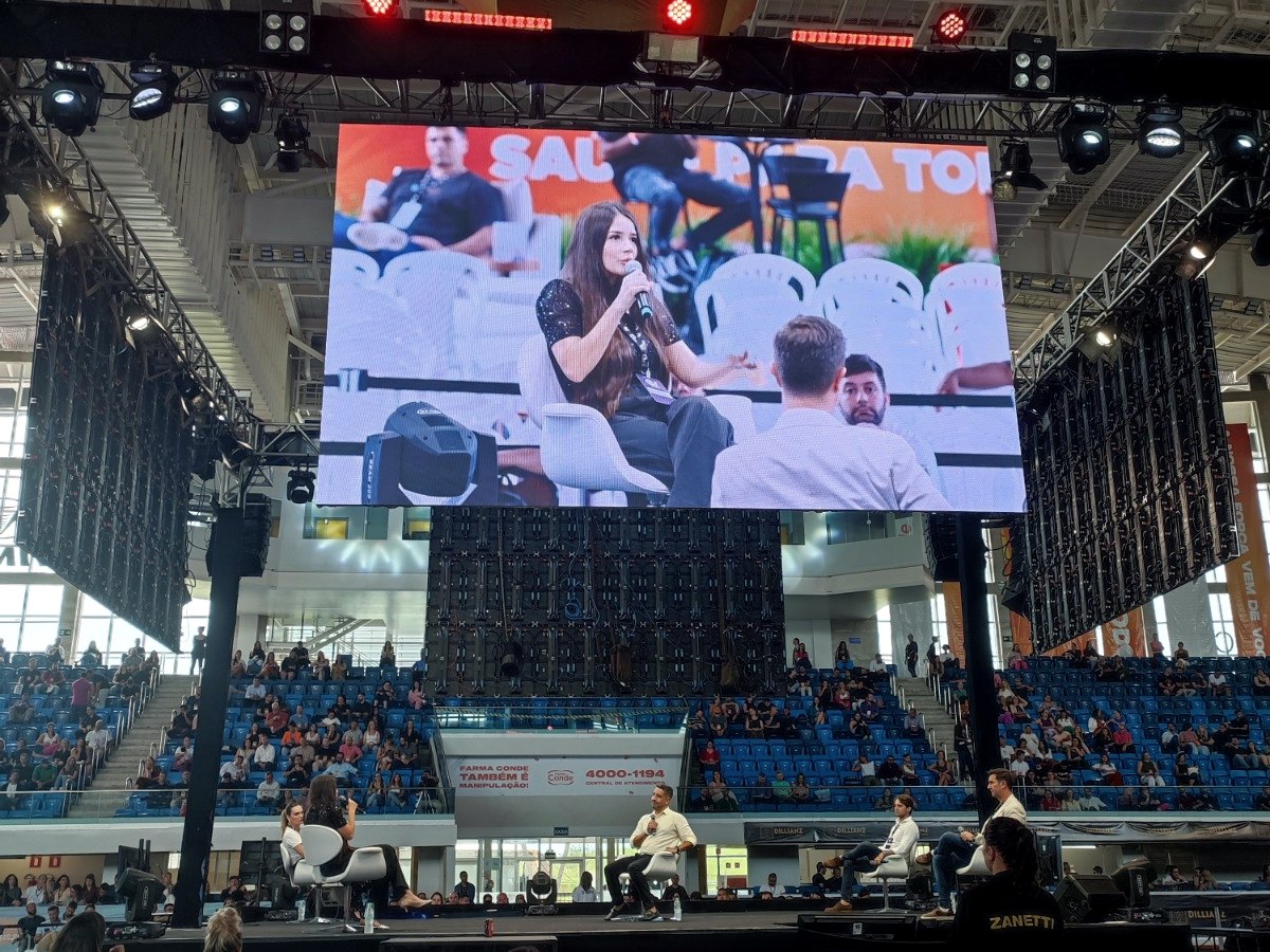 Aline Beringhs em painel no Empreenda Vale: ela aparece no telão e no palco, diante da arena cheia