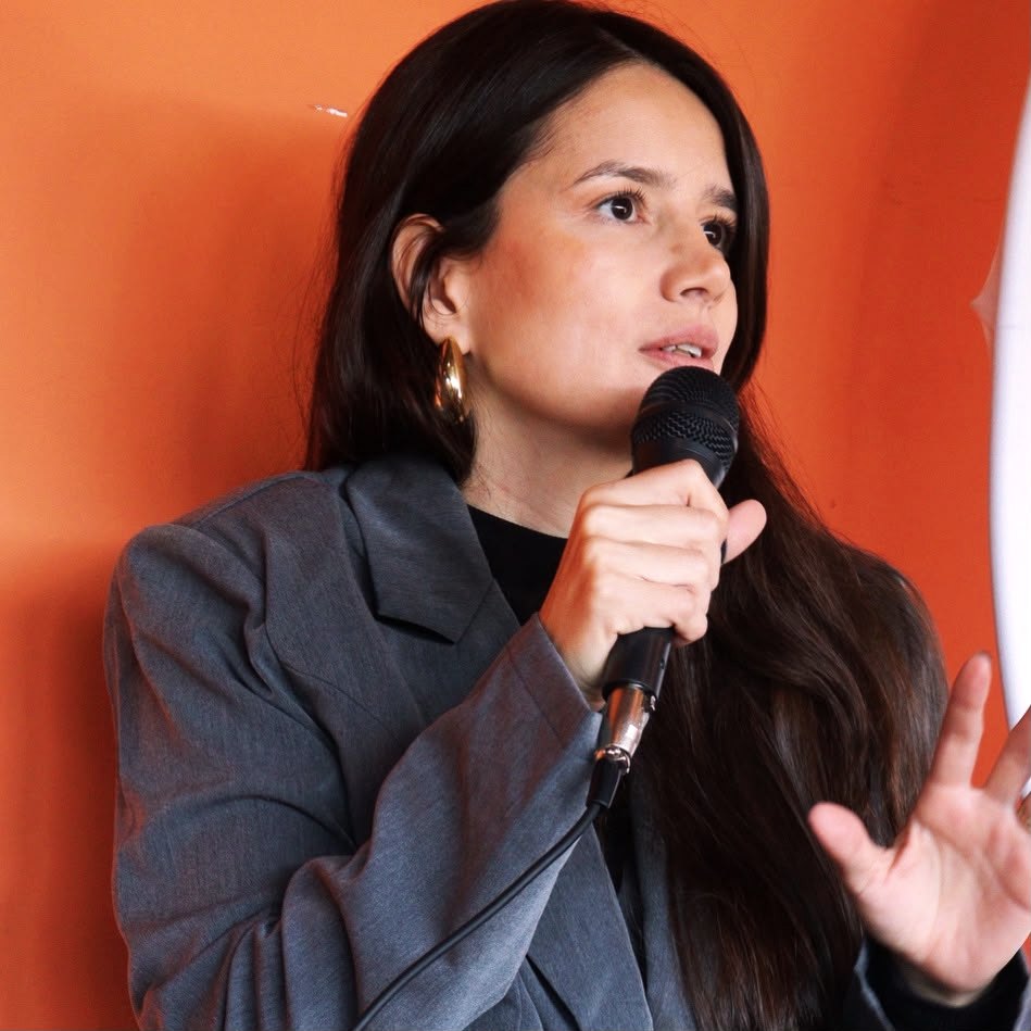 Aline Beringhs falando ao microfone durante um evento